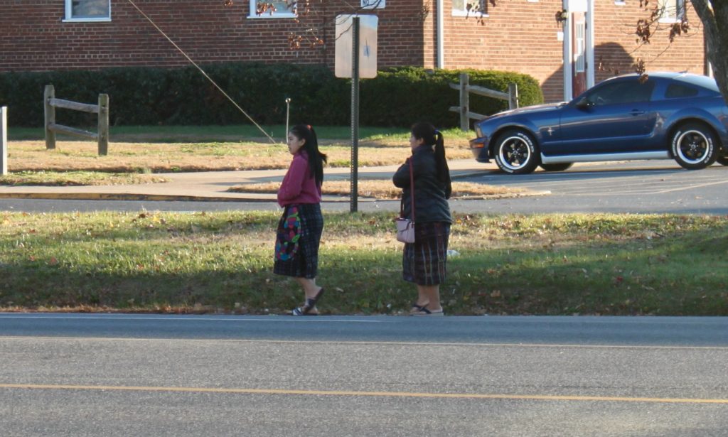 Two women walking on shoulder of road