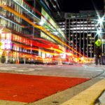 Nightime picture of a bus leaving the Rosslyn Metro Station in NOVA, with a trail of red and orange lights..